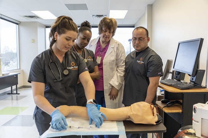 Students and their instructor with a training arm