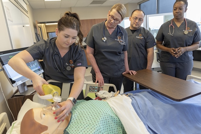 Student practicing on a training dummy while others watch
