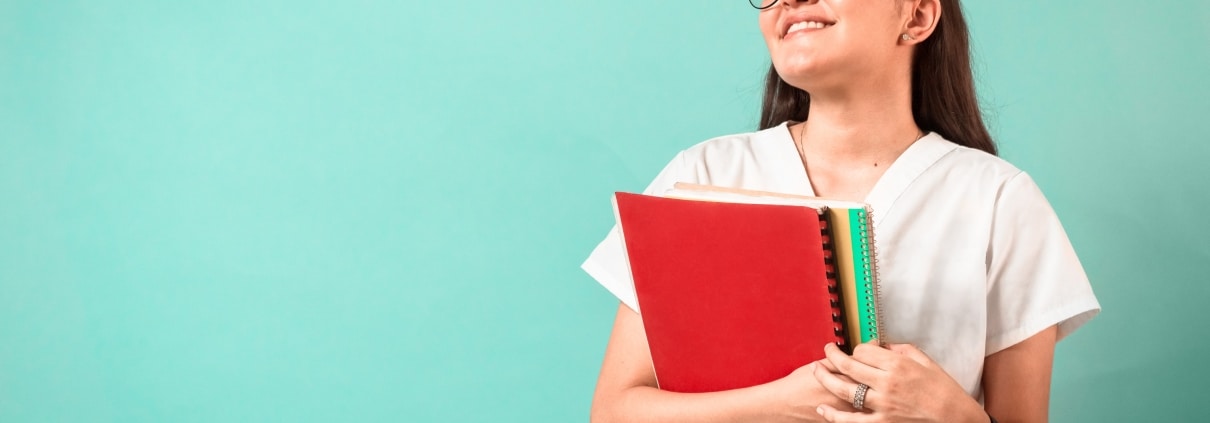 Smiling medical student with textbooks against a blue background