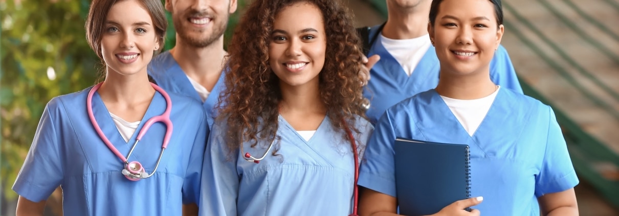 Group of smiling medical professionals in an outside hallway