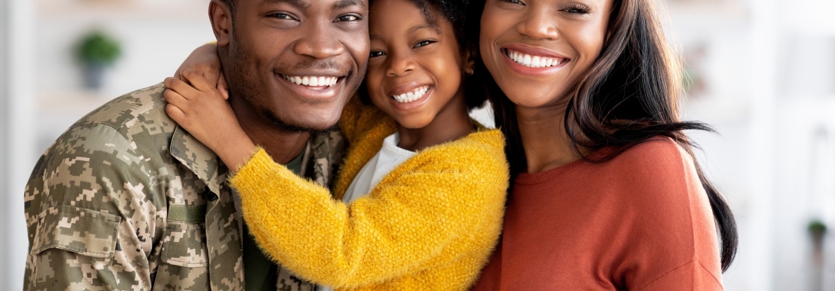 African-American military veteran smiling with wife and daughter