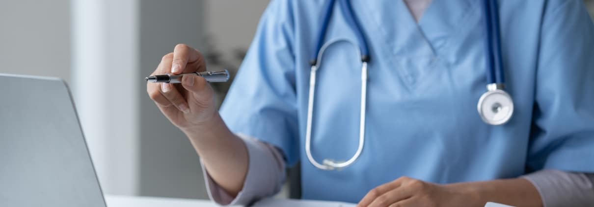 Close up of a female nurse pointing at her laptop with a pen